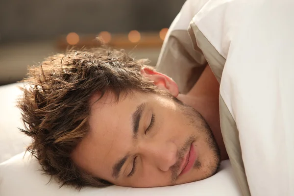 Knappe jonge man slapen in bed — Stockfoto