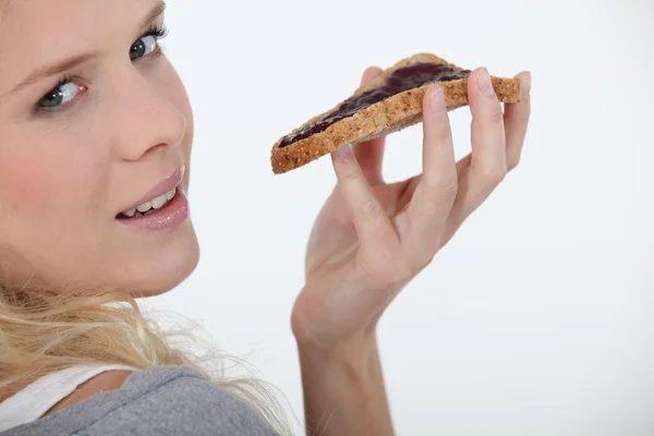 Mulher loira comendo chocolate espalhado no pão — Fotografia de Stock