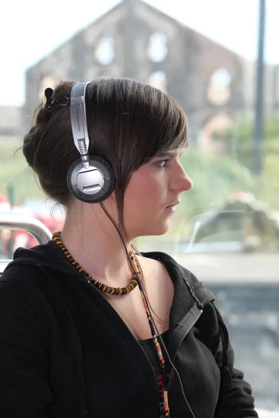 A young woman with headphones on her head. — Stock Photo, Image