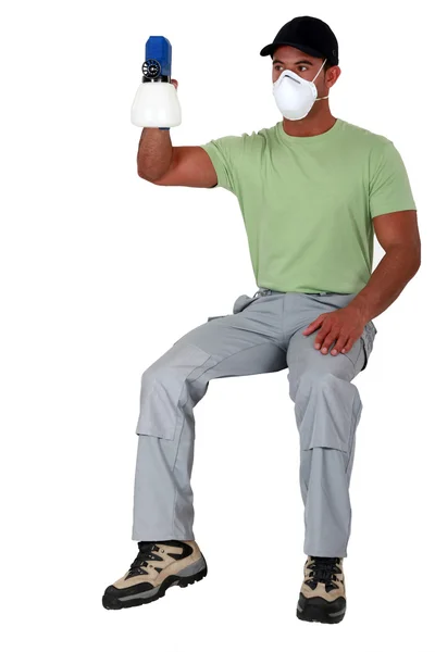 Człowiek siedzący na niewidoczne stołek i trzymając pistolet natryskowy — Zdjęcie stockowe