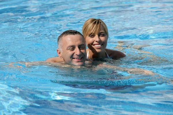 Heureux couple nageant ensemble dans la piscine — Photo