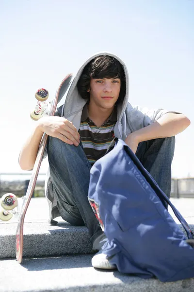 Chlapec sedí na schodech s skateboard — Stock fotografie