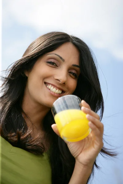 Усміхнена жінка п'є склянку апельсинового соку — стокове фото