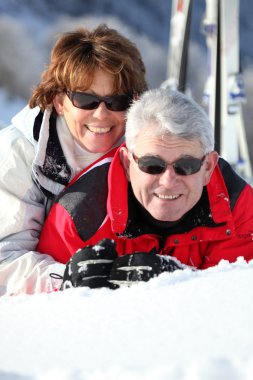 Middle-aged couple having fun on their skiing holiday clipart