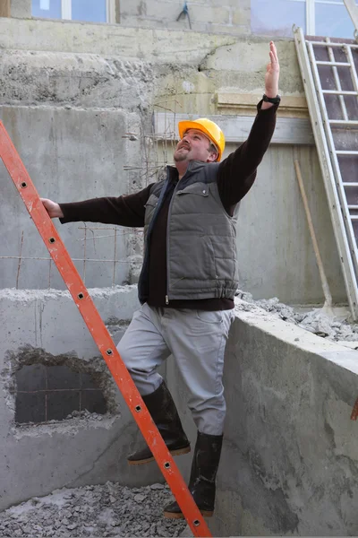 Builder stood by ladder waving — Stockfoto