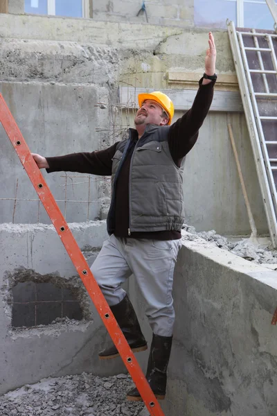 Builder stood by ladder waving — Stockfoto