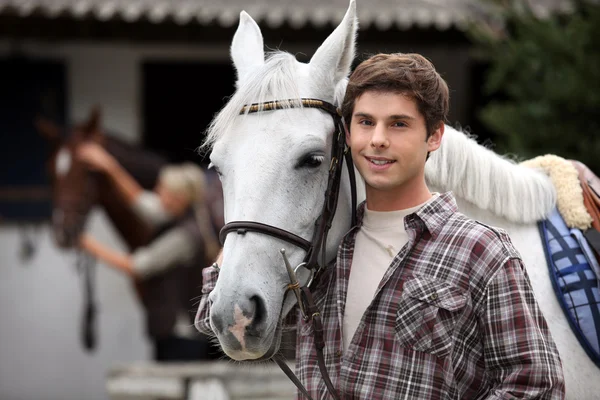 Junger Mann kümmert sich um Pferde — Stockfoto