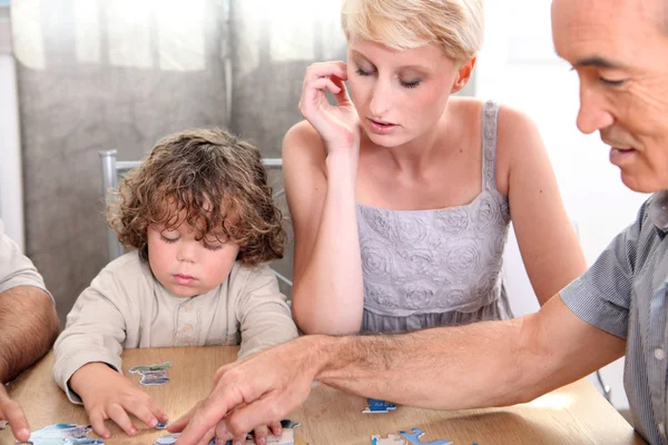 Kind baut Puzzle mit Mutter und Großvater — Stockfoto