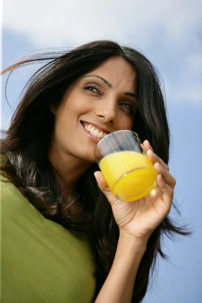 Kvinna som dricker ett glas apelsinjuice — Stockfoto