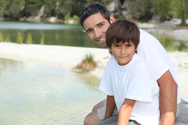 Padre e figlio seduti vicino al lago — Foto Stock