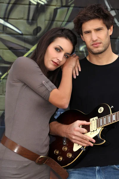 Paar mit Gitarre vor bemalter Wand — Stockfoto
