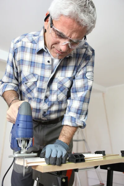 Medelålders handyman sågning av trä — Stockfoto