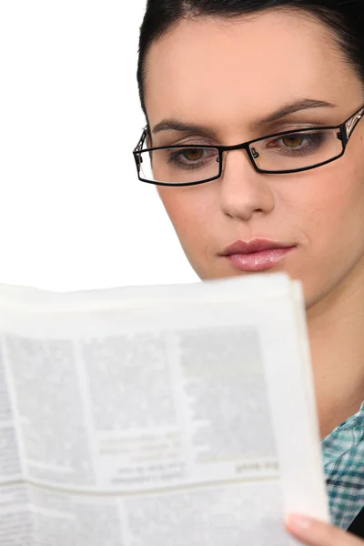 Девушка в очках читает газету — стоковое фото