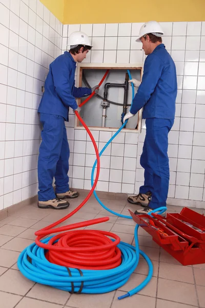 Encanadores instalando novos tubos quentes e frios — Fotografia de Stock