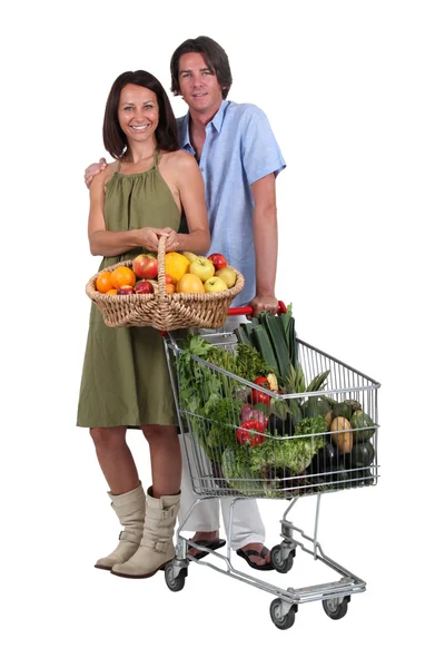 Couple avec un panier et un chariot plein de produits frais — Photo