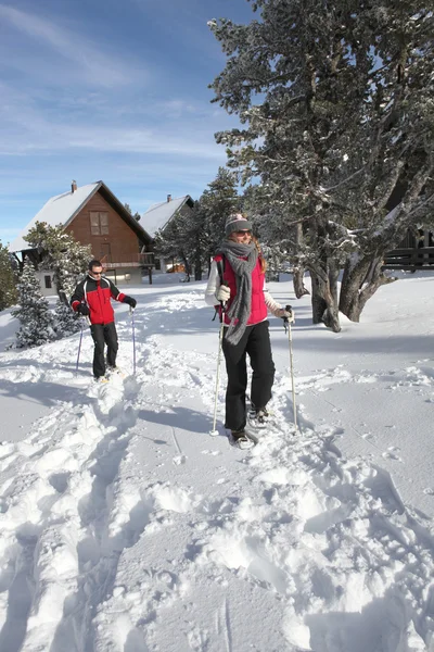 Casal andando em sapatos de neve — Fotografia de Stock