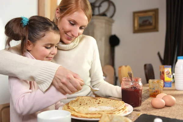 Loving mother making crepes with little girl — Stock Photo, Image