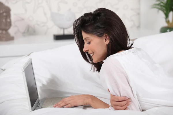 Vrouw met behulp van een laptop op een sofa — Stockfoto