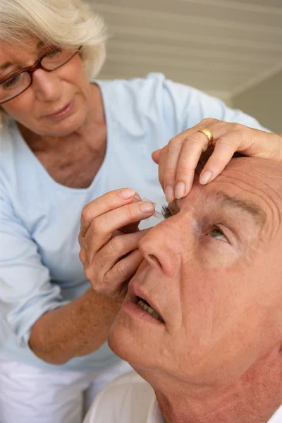 Woman putting eyewash in eyes of a man — Stock Photo, Image