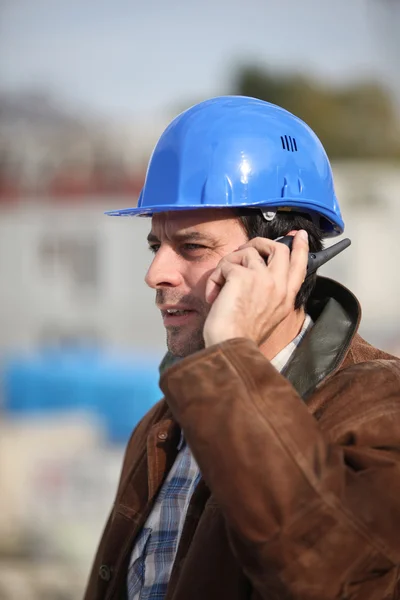Construction worker speaking into his walkie-talkie — Stock Photo, Image