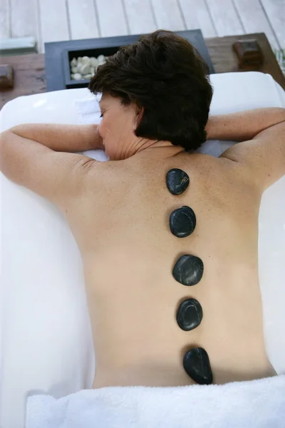 Woman with hot pebbles on her back — Stock Photo, Image