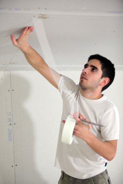 Man masking off ceiling before decorating clipart