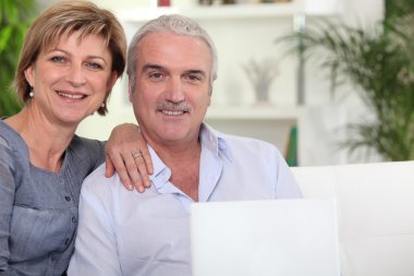 Couple with computer on couch clipart