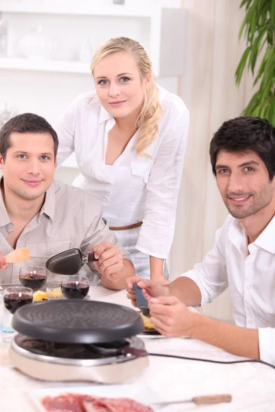 Üç arkadaş bir raclette yeme — Stok fotoğraf