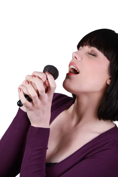 Morena cantando em pincel de maquiagem — Fotografia de Stock