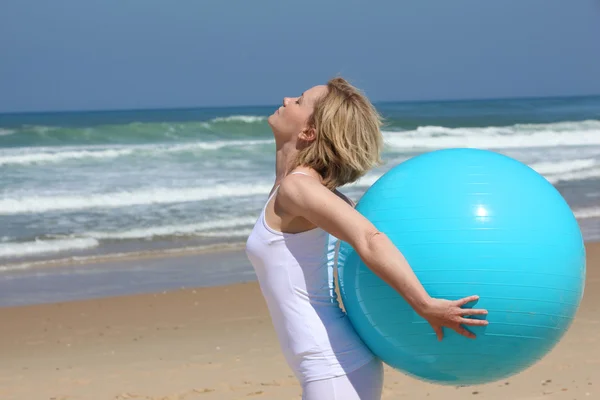 Exercises with blue ball on the beach — Stock Photo, Image
