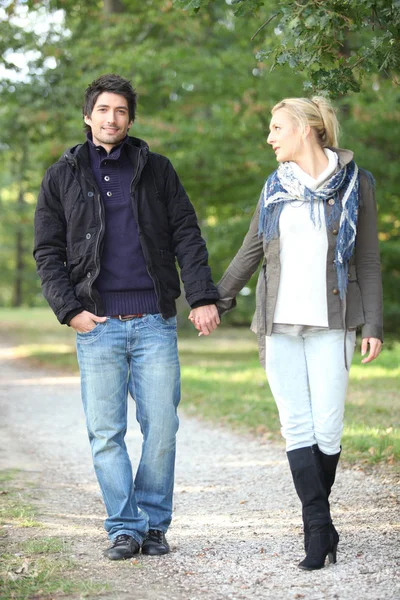 Пара прогулок в парке рука об руку — стоковое фото