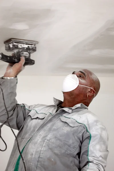 天井を研磨しながら身に着けているマスクを男します。 — ストック写真