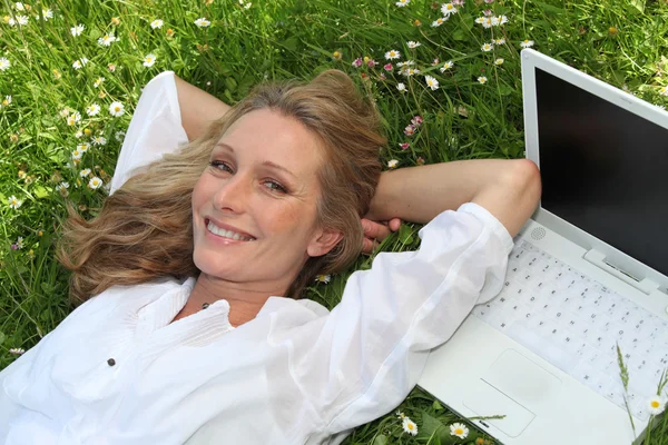 Woman with computer in a field — Stock Photo, Image