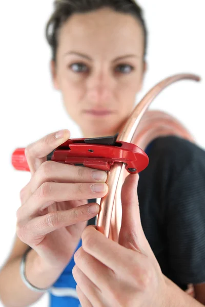 Vrouwelijke loodgieter koperen pijp met speciaal gereedschap snijden — Stockfoto
