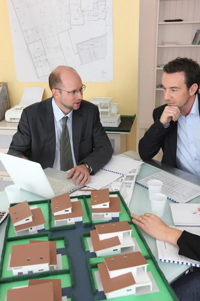 Arquitectos reunidos alrededor de un escritorio intercambiando ideas — Foto de Stock