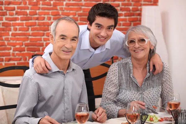 Bejaarde echtpaar en kleinzoon in restaurant — Stockfoto