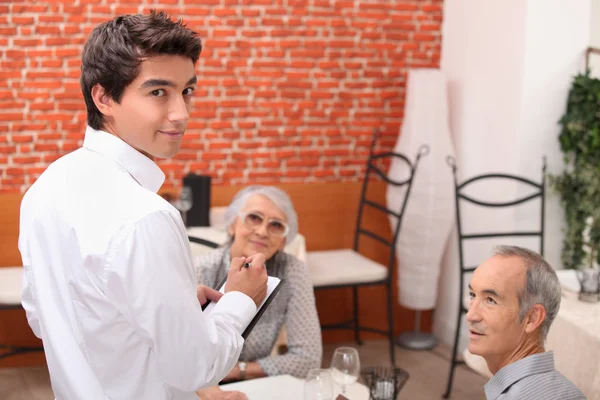 Ouder paar in restaurant met ober — Stockfoto