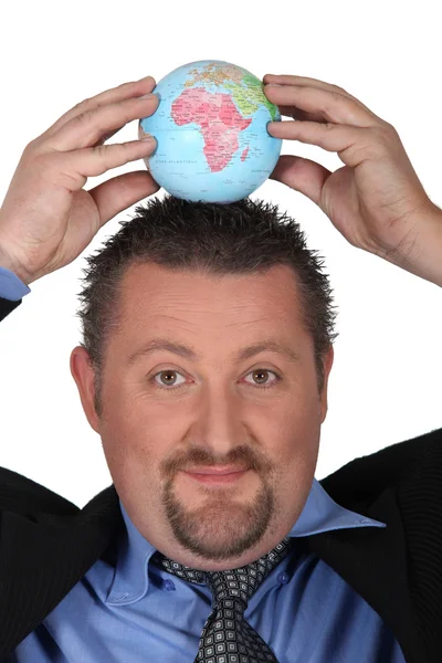 Man in suit putting a globe on his head — Stock Photo, Image
