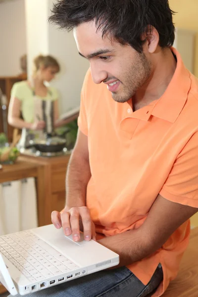 Woman cooking and man with computer — Stock Photo, Image