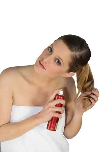 Bare-shouldered blonde wrapped in towel taking care of her hair — Stock Photo, Image