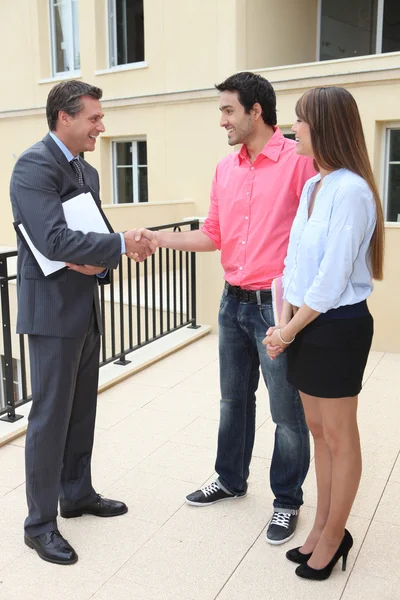 Couple shaking hands with an agent — Stock Photo, Image