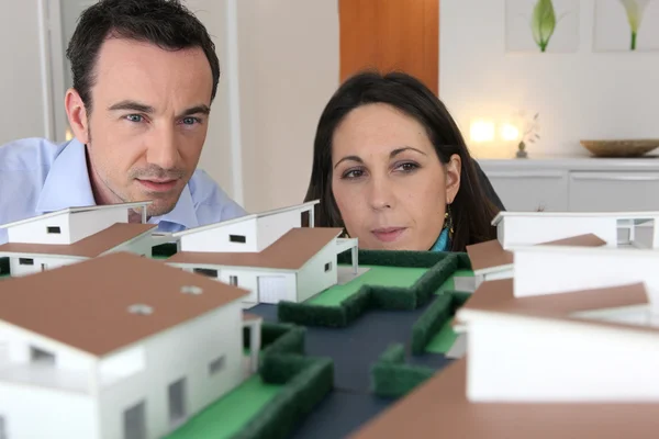 Casal olhando para um modelo de uma propriedade de habitação — Fotografia de Stock