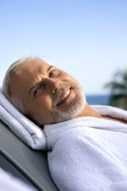 Grey-haired man on sun lounger clipart