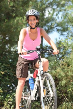 Woman cycling in the forest clipart