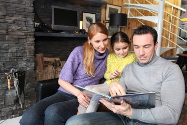 Parents reading a story to their daughter clipart