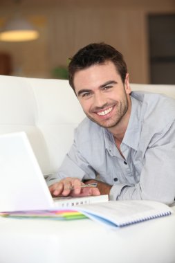 Man lying on sofa with computer clipart