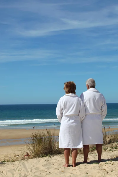 Par i badrockar tittar på havet — Stockfoto