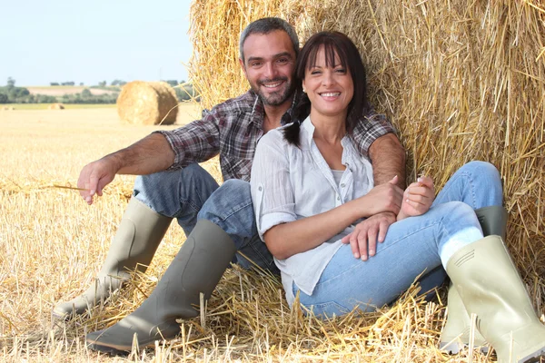 Couple sitting in front of haystack — Stock Photo, Image