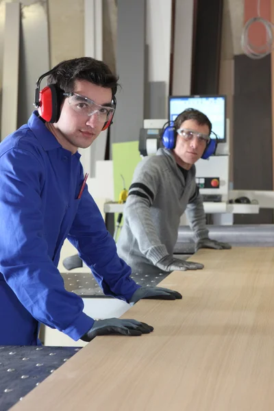 Dos hombres trabajando en una sierra industrial — Foto de Stock