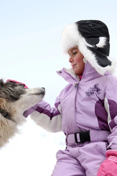 Kleines Mädchen streichelt Hund beim Skifahren — Stockfoto